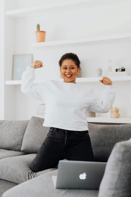 a woman posing with her arms up and holding up a laptop