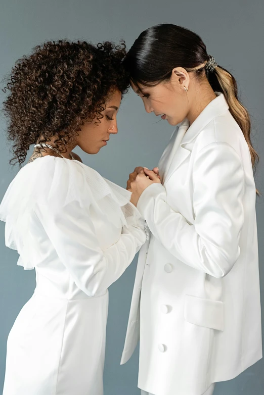 two beautiful young women in white jackets posing together