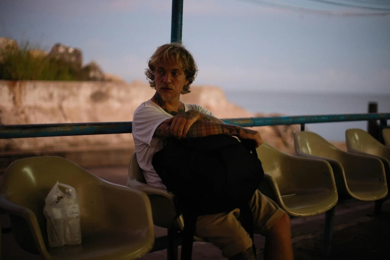 a man sitting down in a chair next to the water