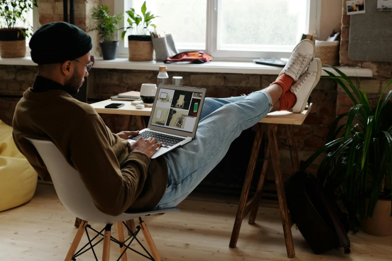 a man sitting on a chair with his feet up while using a laptop