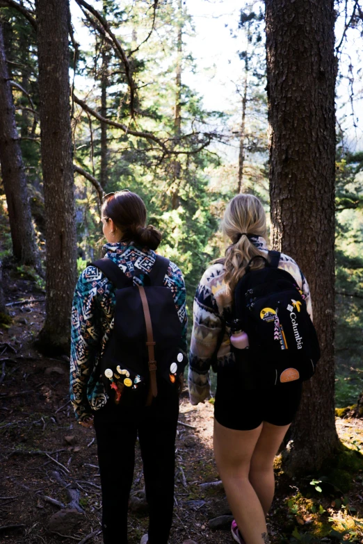 two young women walking on the woods with backpacks on