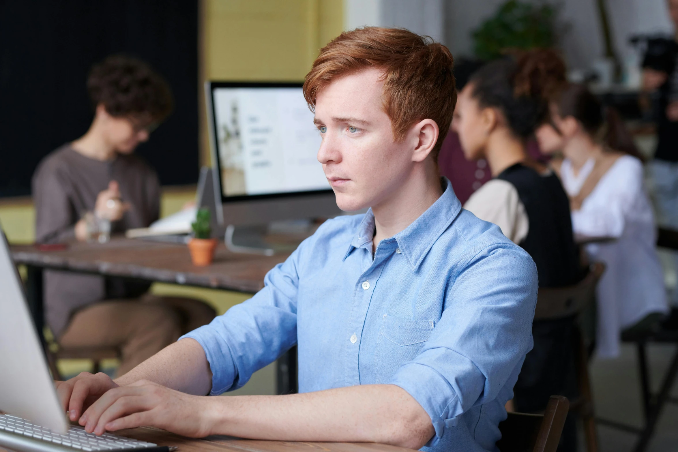 a young man sitting at a table on a laptop computer