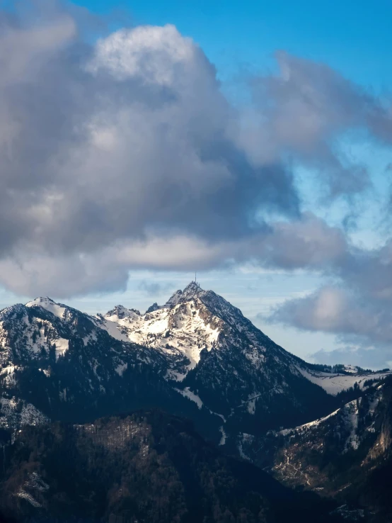 clouds hover over the top of a mountain range