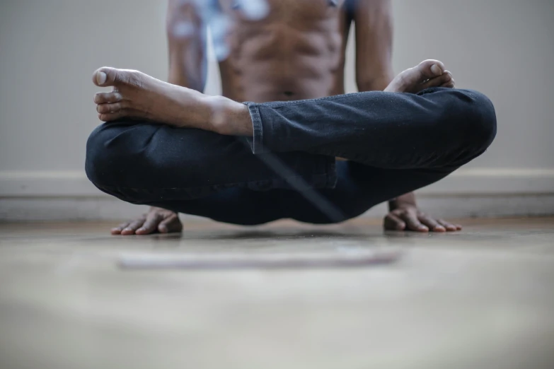 a man sitting on the floor in yoga position with his hands behind him