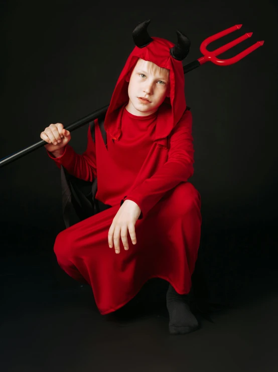 a woman with a devil mask holding a large pitchfork