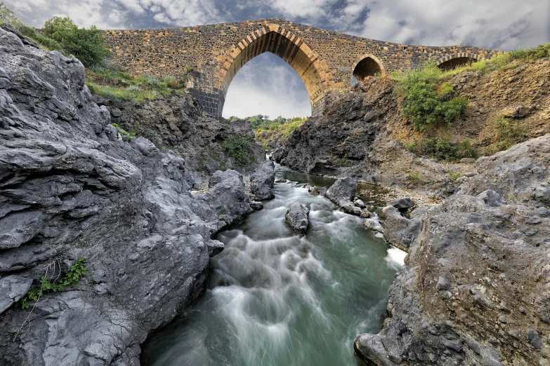 water running under a very old stone bridge