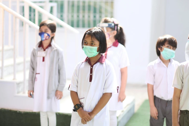 a group of children wearing masks and posing in front of steps