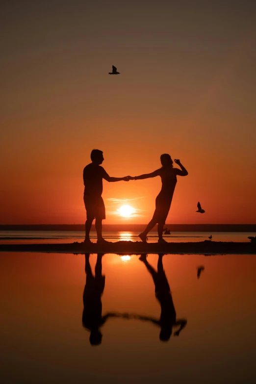 a couple is holding hands as the sun rises