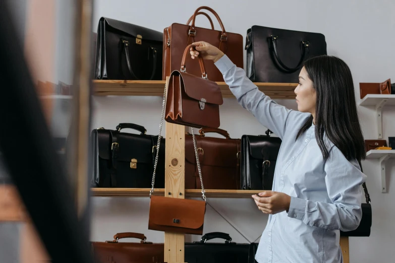 woman selecting handbag on display in store with shelves