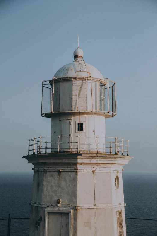 a large white tower is near the ocean