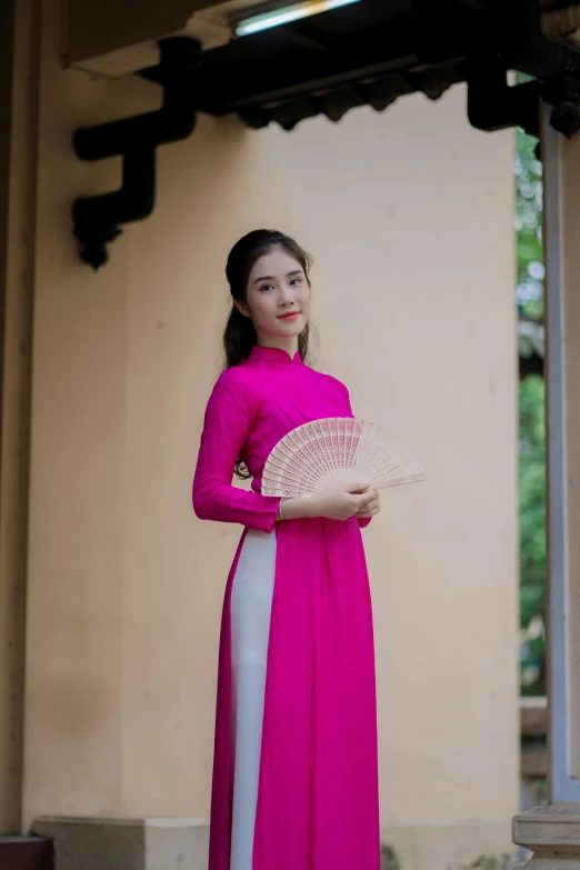 woman in pink with white pants and a fan