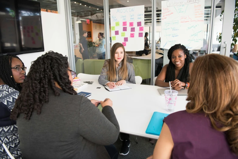 a group of women are gathered at a table with notes