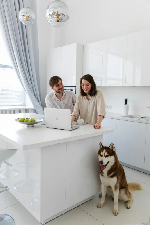 a couple are in the kitchen working on their computers