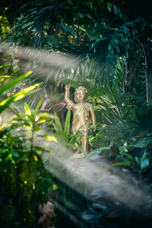 a small golden buddha statue sits in the midst of tropical foliage