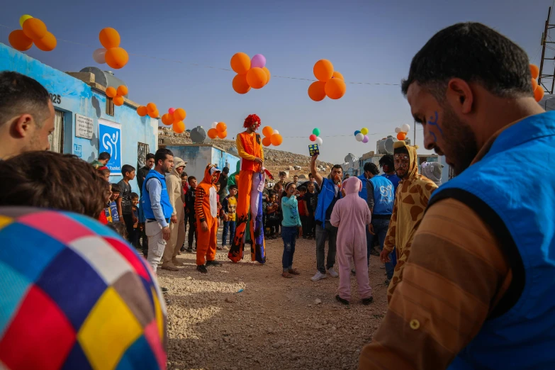 a number of people walking with balloons flying above