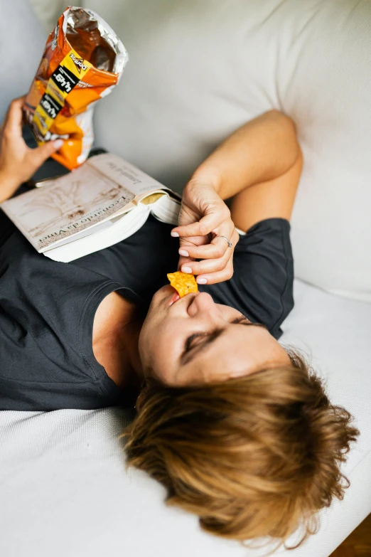 woman on bed eating snacks off of a bag