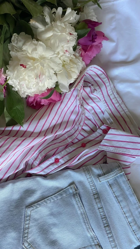 an assortment of items, including a pink  shirt and shorts, laying on top of a sheet