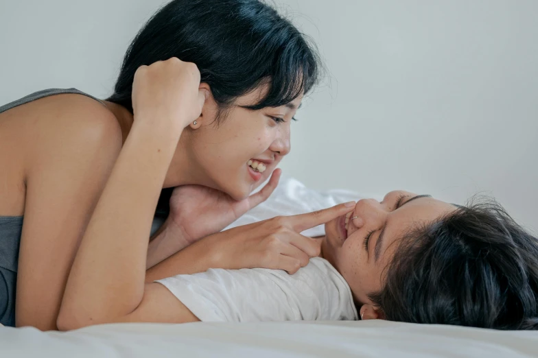 a man and a woman are on the bed, one is holding his head down to another girl