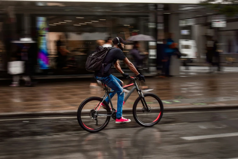 a young man riding his bike down the road in the rain