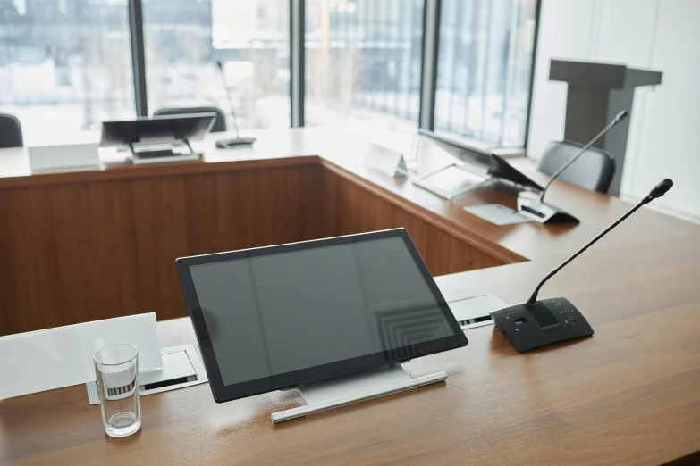 a desk with a monitor, glasses, phone and lamp