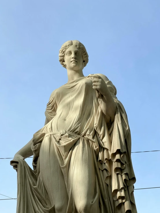 the statue is standing by wires against a blue sky