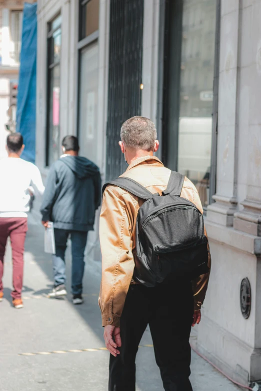 a man with a black backpack walking down the sidewalk