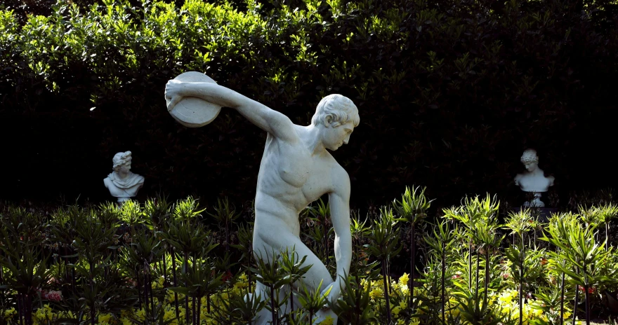 a statue is in some bushes holding a frisbee