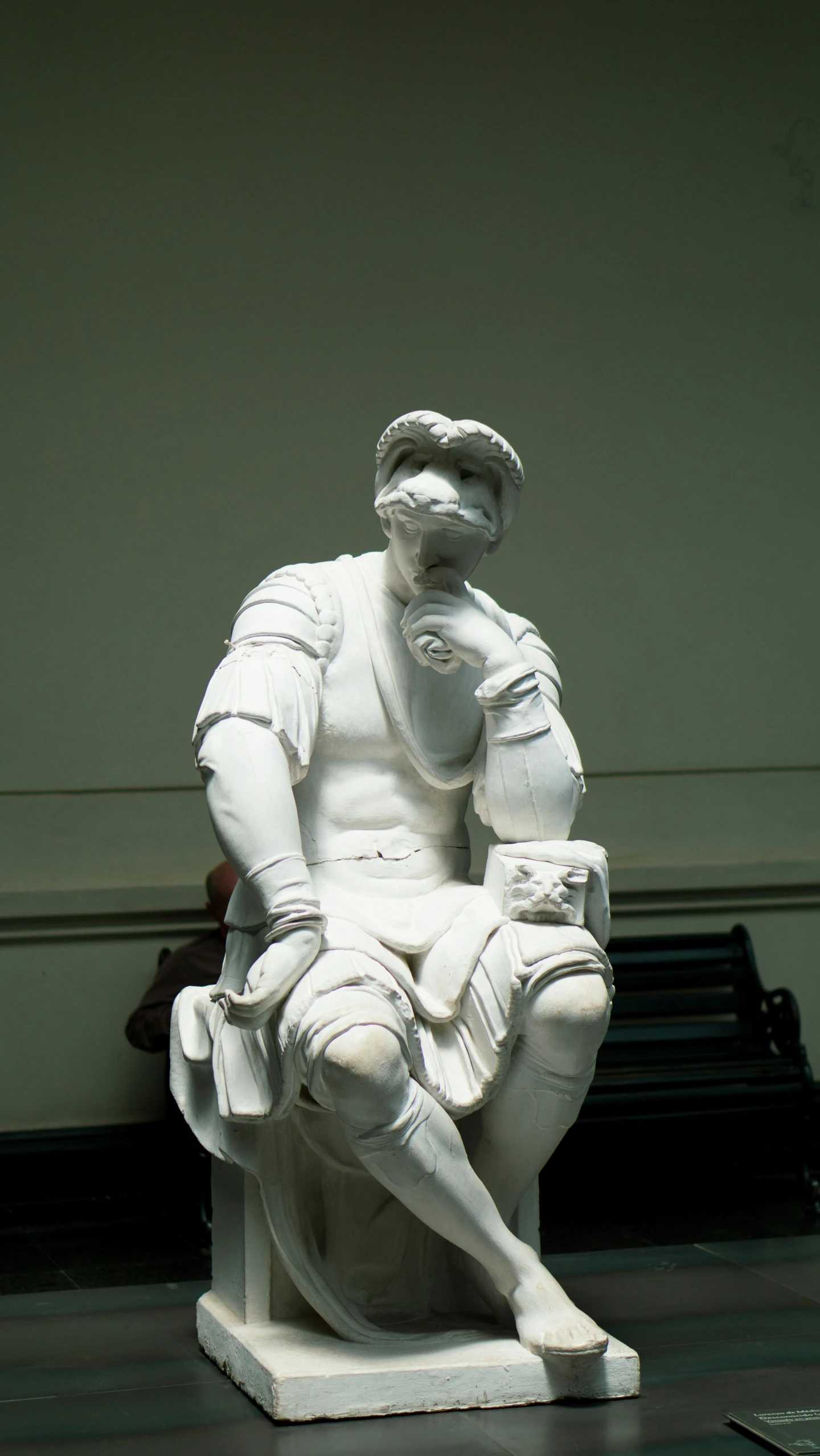 a man in a white baseball uniform sits on a bench