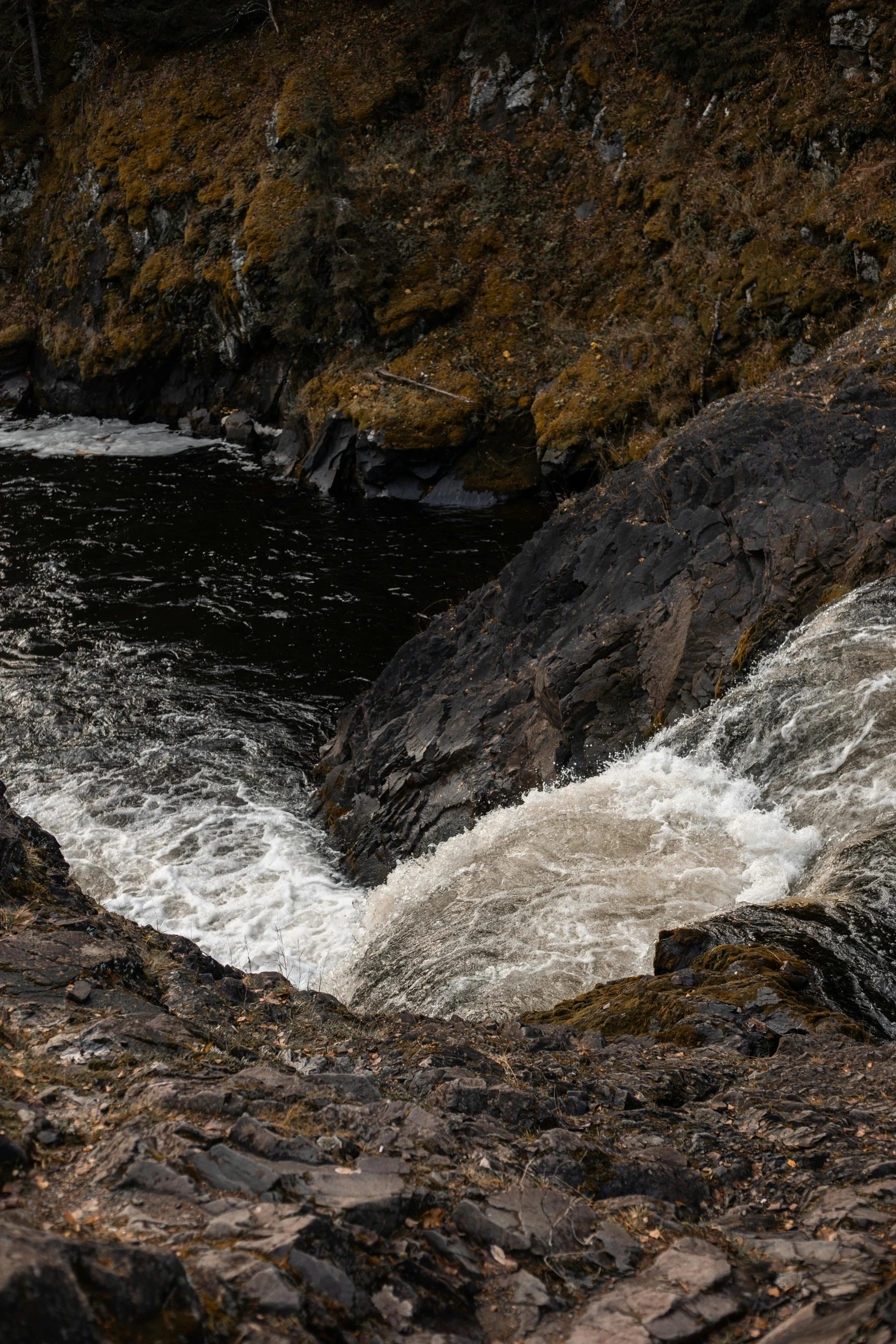 a man is sitting on some rocks by the water