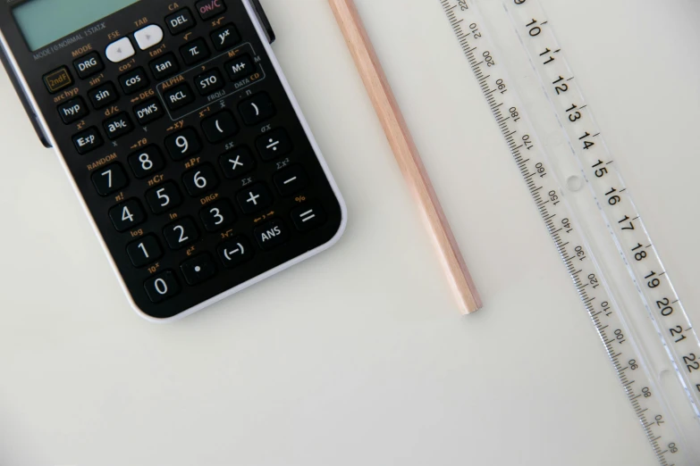 a calculator next to a pencil on a white surface