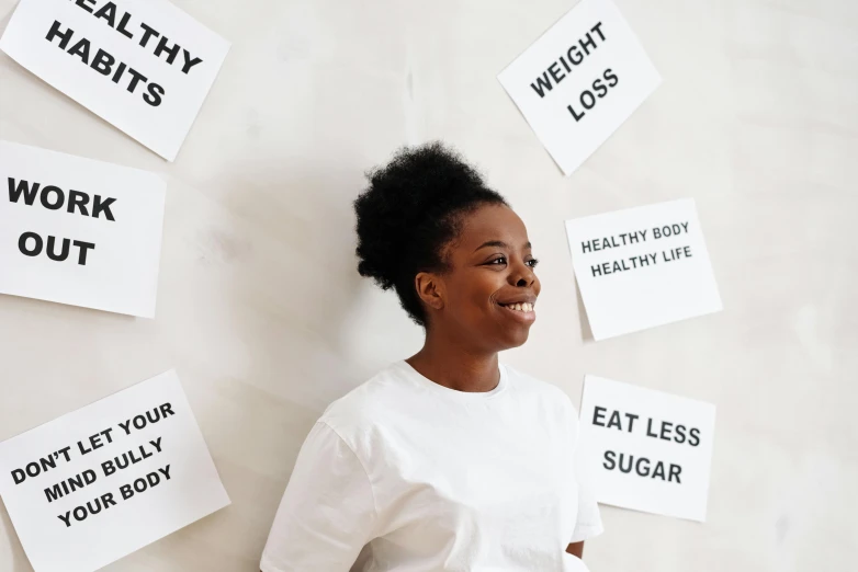 an african american woman smiling near a wall with signs on it