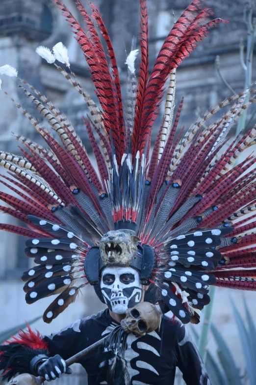 a guy dressed in costume and headdress, walking down the street