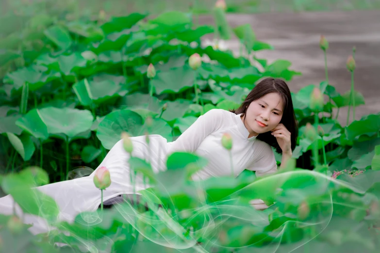 woman laying down in the middle of a sea of green leaves