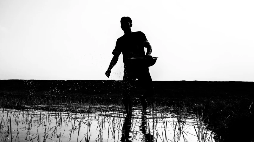 a black and white pograph of a man wading in the water