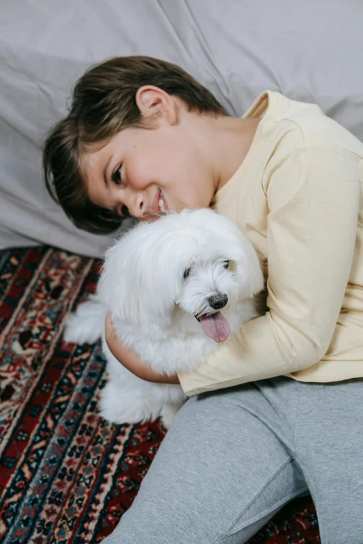 a little girl that is cuddled up to a small white dog