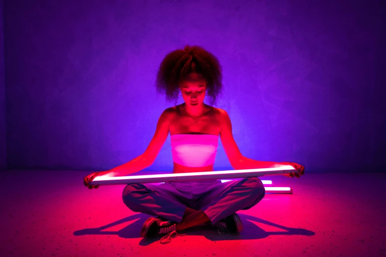 a person sitting in the middle of a floor holding a stick with light coming from it