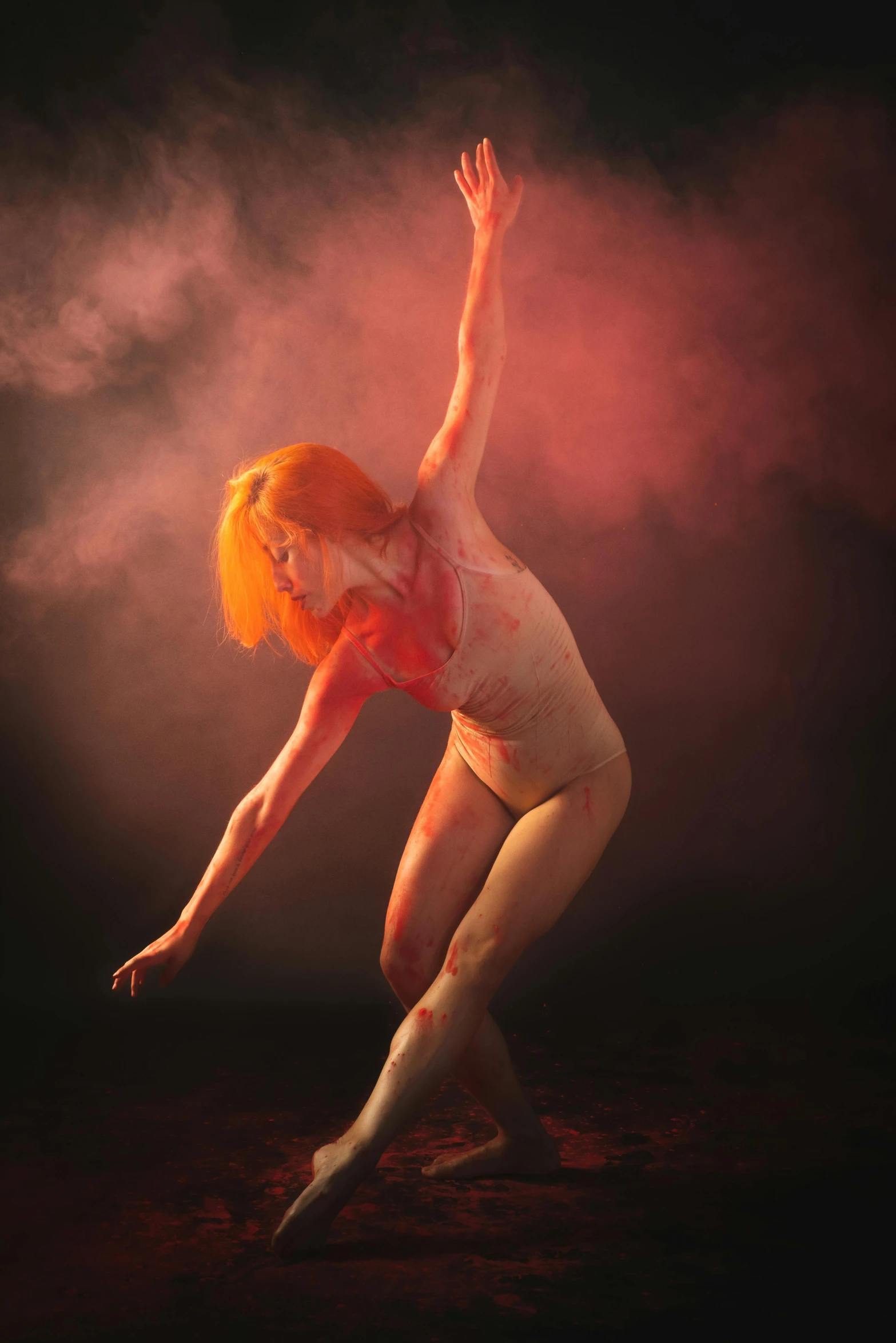 a woman with orange paint is dancing on a black background