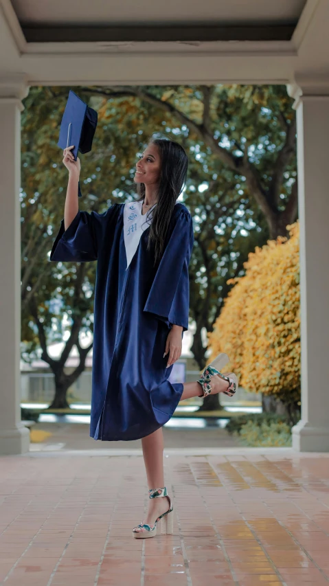 a woman in graduation gown waving her mortars