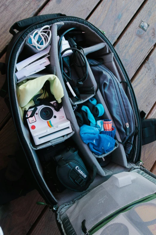 a back pack full of gadgets on a wooden floor