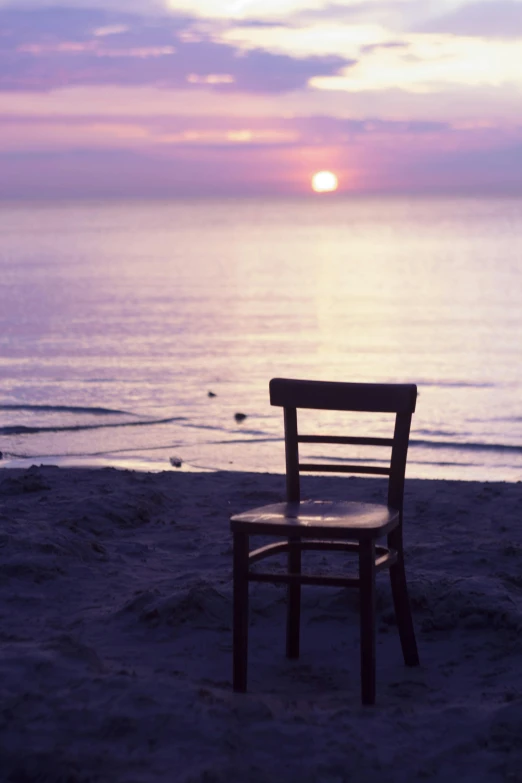 a beach with a chair and a body of water in the background