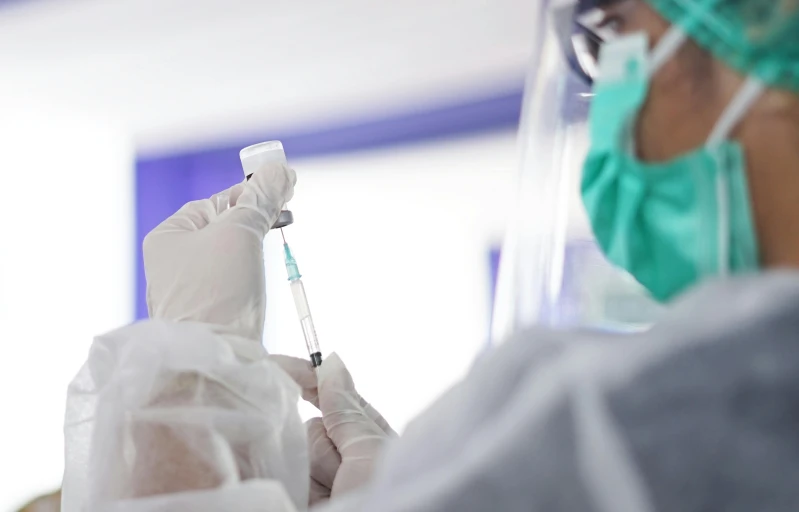 two doctors in green coats and face masks operating an oxygen tube