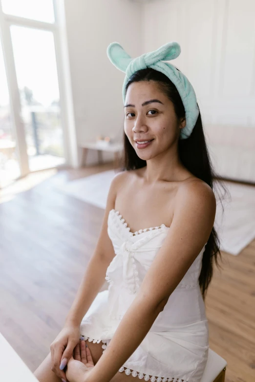 young woman sitting on top of a wooden chair in a room