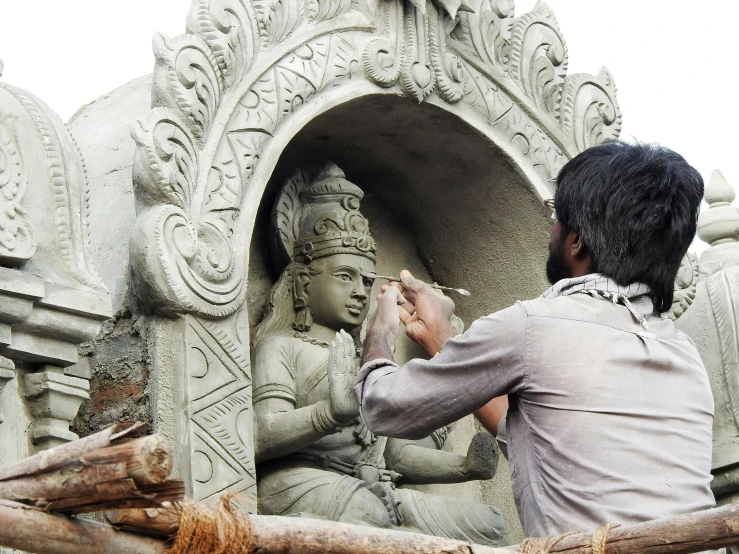 a man is putting sand on his statue