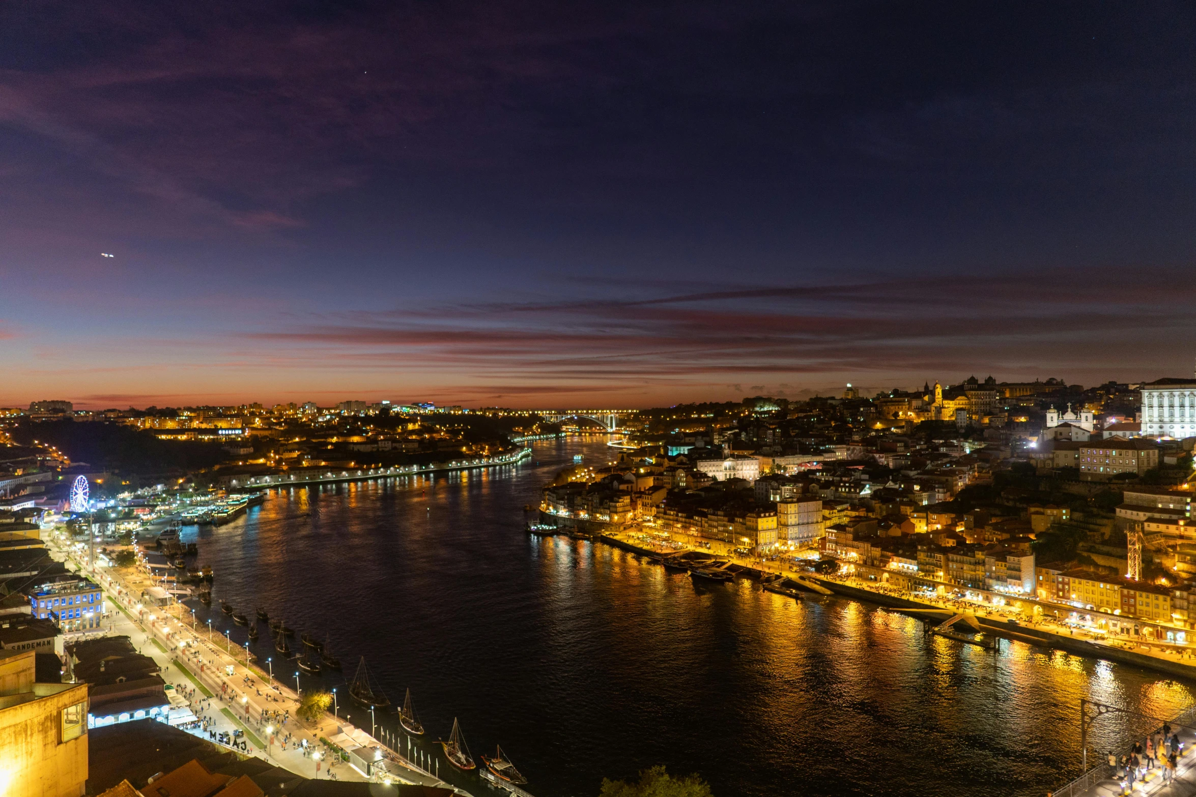 a view over the city lights at night from a hill overlooking a river