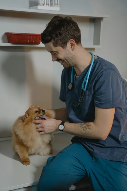a dog sitting on the ground next to a male wearing scrubs