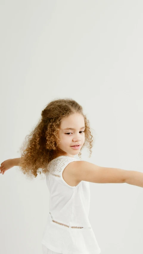 girl in a white tank top with her arms extended up to the side