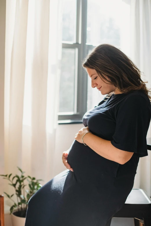 a pregnant woman in black clothing by a window