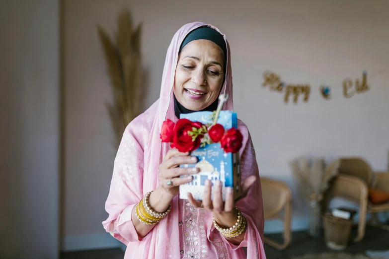 a woman in pink holding a card next to flowers