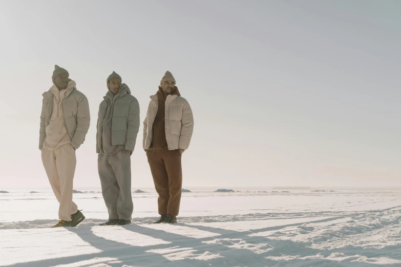 three men are standing in the snow looking toward the sky