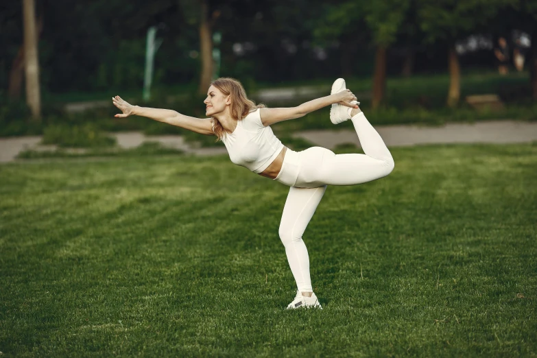 a woman practices yoga in a grassy field